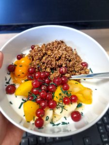 Schoko-Müsli-Bowl mit Joghurt, Johannesbeeren, Pfirsich, Bananen, Physalis, Quinoa und feinem Spirulina-Granulat